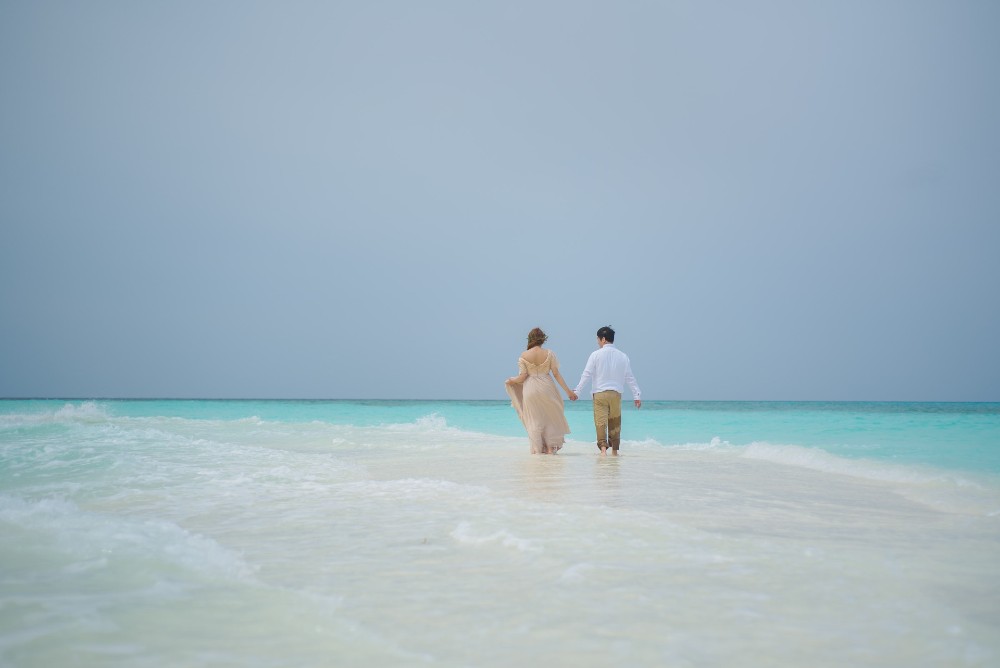 Bodas en cancun:Pareja caminando de la mano a la orilla del mar después de su boda en Cancún
